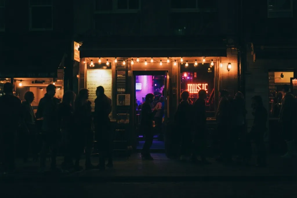 夜晚的城市音乐酒吧门口灯光与人群剪影，旅行氛围